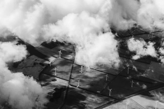 an aerial view of a wind farm surrounded by clouds